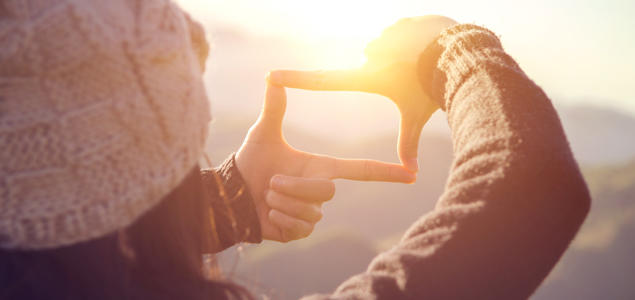 Foto: iStock Jente som former fingrene som et vindu mot solen